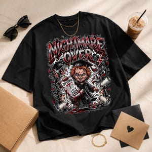 May include: Black t-shirt with a graphic featuring a cartoon character in a graduation gown holding a diploma that reads "Class of 2026." The text "Nightmare Over" is displayed in red and white. The design includes graduation caps and lightning bolts.