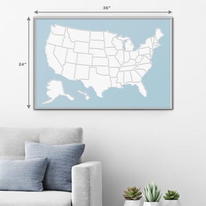 May include: A white outline map of the United States with state borders, on a light blue background. The map is framed in a silver frame and measures 24 inches by 36 inches.