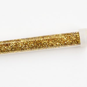 May include: A clear plastic tube filled with gold glitter.