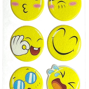 May include: Sheet of yellow emoji stickers with various expressions, including winking, licking lips, kissing, and crying. The stickers have a glittery finish and a small rectangular label with the text "XYK095".