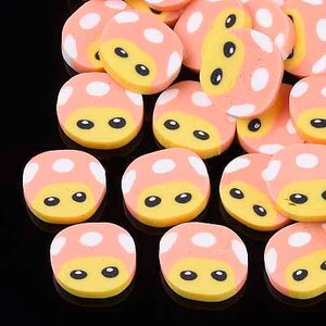 May include: A collection of small, round, pink and white mushroom-shaped resin cabochons with yellow faces and black eyes.