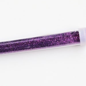 May include: A small clear tube filled with purple glitter.