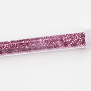 May include: A clear plastic tube filled with pink glitter.