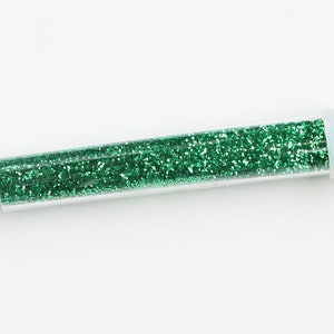 May include: A clear plastic tube filled with green glitter.