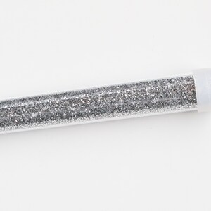 May include: A clear plastic tube filled with silver glitter.