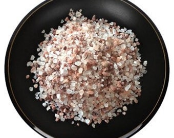 May include: A close-up view of pink Himalayan salt crystals, a type of rock salt, in various sizes. The salt is a light pink color and has a rough texture.