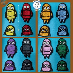 Könnte beinhalten: Eine Sammlung farbenfroher, gestickter Aufnäher in Gelb, Rot, Orange, Blau, Lila, Schwarz, Rosa und Grün. Jeder Aufnäher zeigt ein roboterähnliches Design, mit einer Höhe von 5,5 cm und 3 cm. Die Aufnäher sind auf blauem Hintergrund angeordnet.