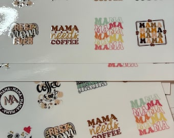 May include: A collection of adhesive decals on white sheets featuring various designs with the word Mama, coffee-themed graphics, and phrases like but first COFFEE, Hot Mess MOM, BEST MOM EVER, and MAMA needs COFFEE in diverse fonts and colors.
