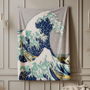 May include: A rectangular tapestry displaying Hokusai's "The Great Wave off Kanagawa." The image shows a large wave in blue, teal, and white, with a mountain in the background. The tapestry is hung on a neutral-toned wall, creating a focal point.