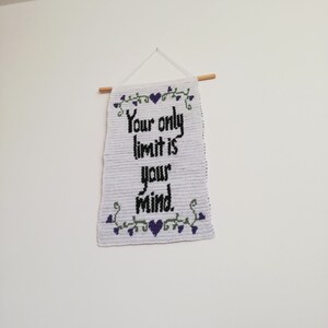 Pu&ograve; includere: Un arazzo da parete in crochet bianco con una citazione ricamata in nero che recita "Your only limit is your mind." La citazione &egrave; circondata da un tralcio verde con cuori viola.