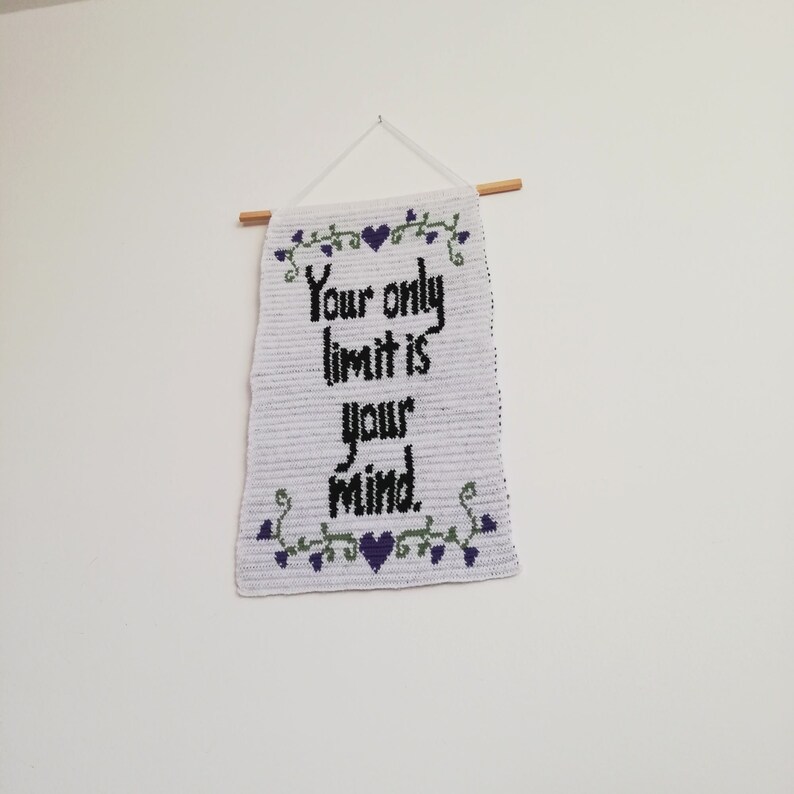 Pu&ograve; includere: Un arazzo da parete in crochet bianco con una citazione ricamata in nero che recita "Your only limit is your mind." La citazione &egrave; circondata da un tralcio verde con cuori viola.