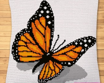 Op de afbeelding: Een vierkant wit sierkussen met een gepixelde monarchvlinder-afbeelding in oranje, zwart en wit. De vlinder is gecentreerd op het kussen, dat een klein rechthoekig label bevat met de tekst SYMBOLIC IMAGE, NOT A PHOTO!
