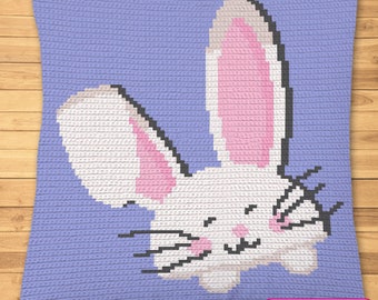 May include: A purple crocheted pillow with a white bunny rabbit with pink ears and whiskers. The bunny is smiling and has its eyes closed. The pillow has the text "SYMBOLIC IMAGE, NOT A PHOTO!" in the bottom right corner.