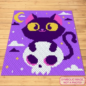 Peut inclure: Un motif de crochet violet avec un chat noir assis sur un crâne blanc. Le chat a des oreilles roses et des yeux jaunes. L'arrière-plan est violet avec des nuages blancs et des étoiles jaunes.