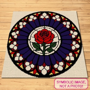 May include: A square rug featuring a circular stained glass window pattern. The center displays a red rose with green leaves, surrounded by concentric rings of deep blue, red, yellow, and white segments, all outlined in thick black lines.