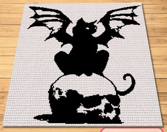 May include: Black and white crochet pattern of a cat with wings sitting on a skull. The cat has a pointed tail and large wings. The skull has a large eye socket and a prominent jaw.