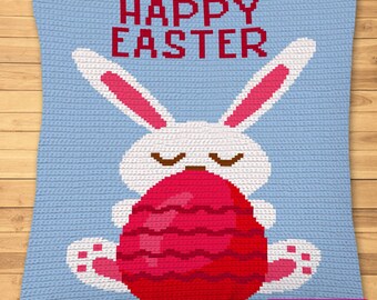May include: A blue crochet pillow with a white bunny holding a red and pink Easter egg. The pillow has the text "Happy Easter" in red.