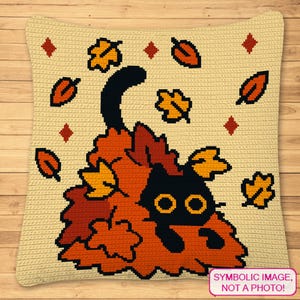 May include: A cream-colored, square crochet pillow featuring a black cat nestled in a pile of autumn leaves. The leaves are in shades of orange, yellow, and brown. The cat has large yellow eyes. The pillow has a decorative leaf and diamond pattern.