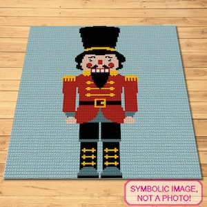 Puede incluir: Imagen pixelada de un soldado cascanueces sobre un fondo azul claro. El cascanueces lleva una chaqueta roja con detalles dorados, pantalones negros y un sombrero alto negro. Incluye el texto "IMAGEN SIMBÓLICA, ¡NO ES UNA FOTO!"