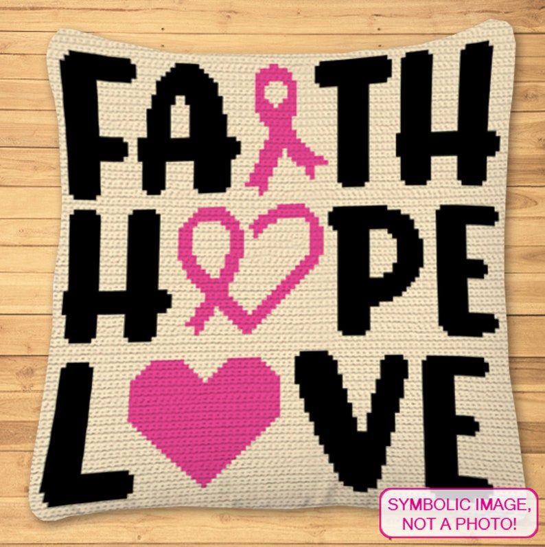 May include: A crocheted pillow with the words "Faith Hope Love" in black letters. The words are surrounded by pink ribbon symbols and hearts.