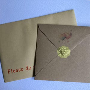 May include: A square brown envelope with a gold wax seal featuring a heart design and a small watercolor heart illustration, paired with a larger rectangular brown envelope with the red printed text Please do not bend on the lower left corner.