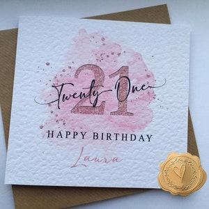 K&ouml;nnte beinhalten: Eine rosa und wei&szlig;e Karte mit einem Aquarelldesign und der Zahl 21 in goldenen Glitzer. Der Text "Twenty-One" ist in Kursivschrift &uuml;ber der Zahl geschrieben. Der Text "Happy Birthday Laura" ist unter der Zahl geschrieben.