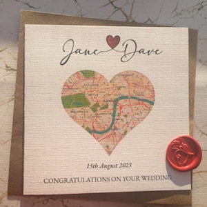 May include: A wedding card featuring a heart-shaped map of London, with the names "Jane" and "Dave" above. The date "15th August 2023" and the message "Congratulations on your wedding" are printed below. A red wax seal is on the bottom right corner.