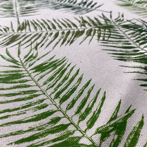 May include: White fabric with a green fern leaf pattern. The fabric has a subtle texture.