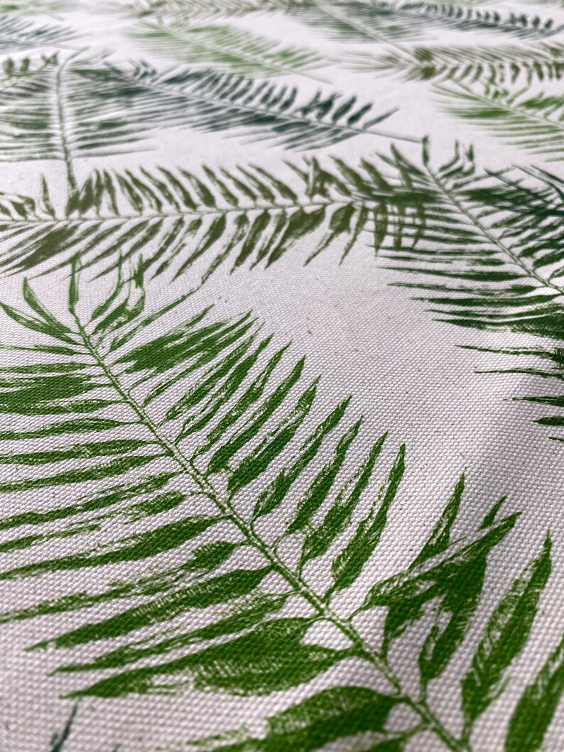 May include: White fabric with a green fern leaf pattern. The fabric has a subtle texture.