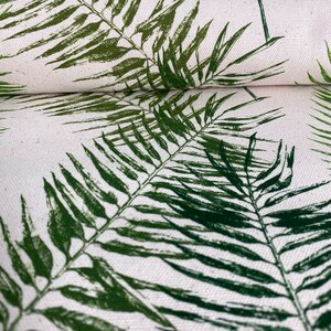 May include: Green palm leaf print fabric with a white background. The fabric is folded in half, showing the pattern on both sides.