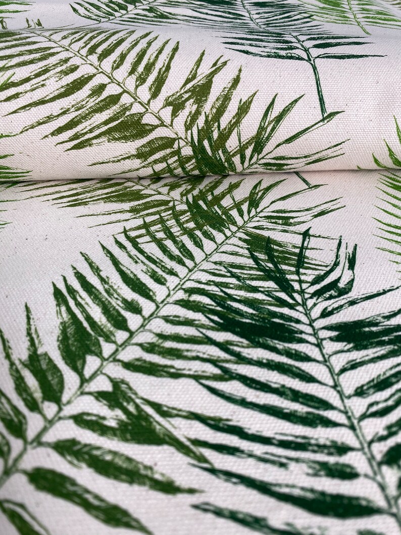 May include: Green palm leaf print fabric with a white background. The fabric is folded in half, showing the pattern on both sides.