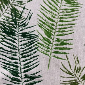 May include: A white fabric with a repeating pattern of green palm leaves. The fabric is measured with a ruler in inches.