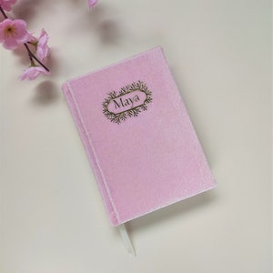 May include: A pink velvet journal with a gold bookmark and the name "Maya" embossed on the front cover.
