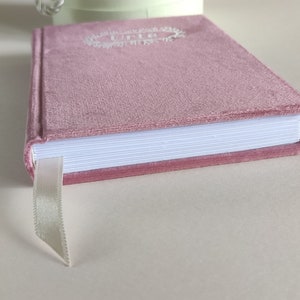 May include: A pink velvet journal with a white ribbon bookmark. The cover features a white embroidered design with the word "Life" in the centre.