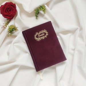 May include: Burgundy velvet journal with a gold foil design and the name "Just&eacute;" written in cursive.