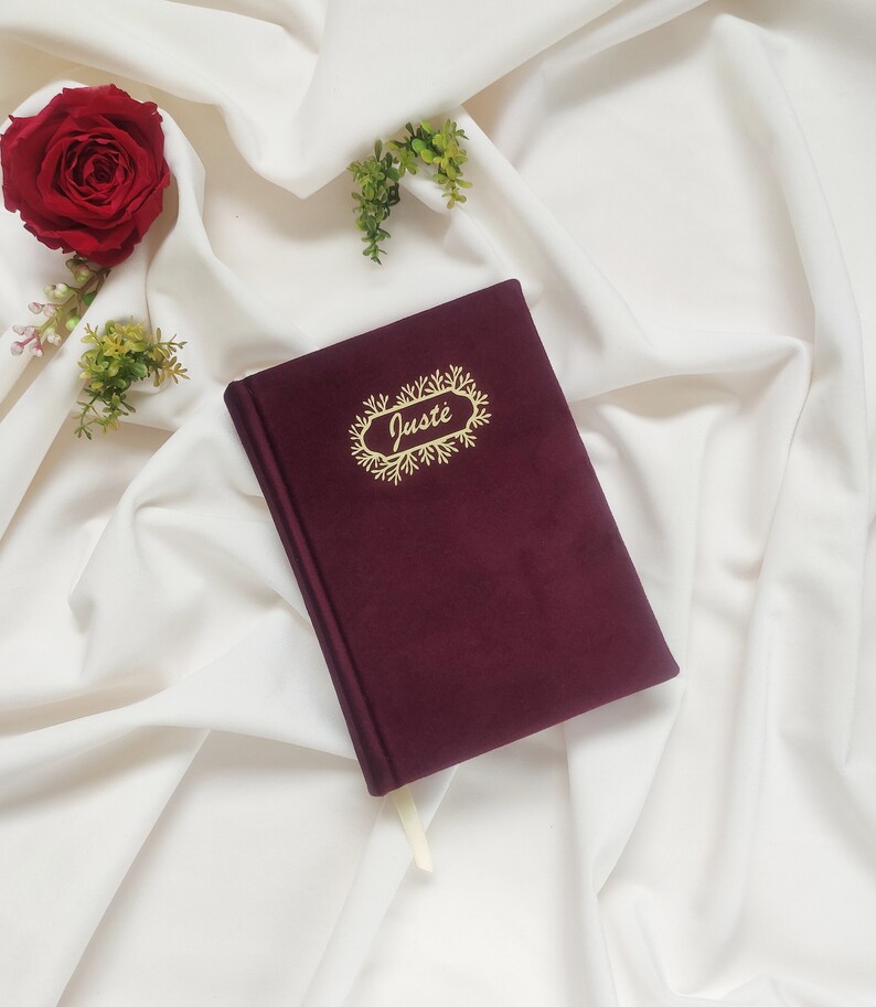 May include: Burgundy velvet journal with a gold foil design and the name "Just&eacute;" written in cursive.