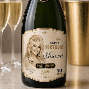 May include: A dark green champagne bottle with a custom label featuring a portrait of Dolly Parton, the text Happy Birthday Sharon, Dolly Approved, 2nd September 1976, and 50 Today. The label includes gold accents, small cowboy hat icons, and stars.