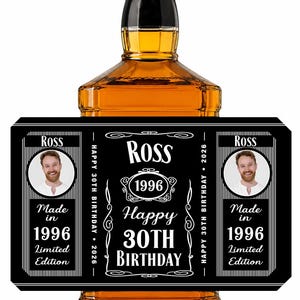 May include: A square glass bottle filled with amber liquid featuring a black rectangular label. The label displays the name Ross, the year 1996, and the text Happy 30th Birthday 2026. It includes two circular portraits of a man and the text Made in 1996 Limited Edition.