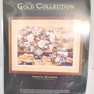 May include: A sealed embroidery kit titled The Gold Collection Oriental Splendor by Lena Liu. The package displays a finished floral still life design featuring a vase and jar on a table. Text includes dimensions of 20 inches by 14 inches.
