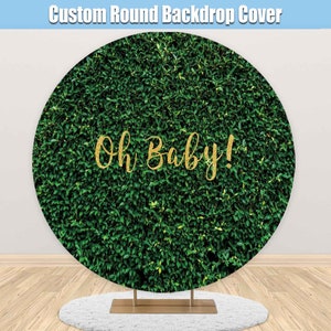 May include: Round green backdrop with the text "Oh Baby!" in gold glitter lettering. The backdrop is made of a green leafy pattern.