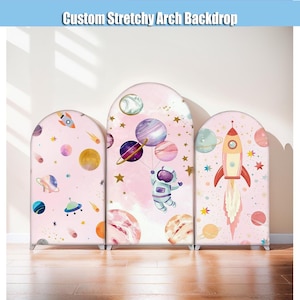 Puede incluir: Tres fondos de arco elásticos personalizados con temática espacial. Cada fondo presenta un fondo rosa con planetas, estrellas, cohetes y un astronauta. El texto "Custom Stretchy Arch Backdrop" está en la parte superior.