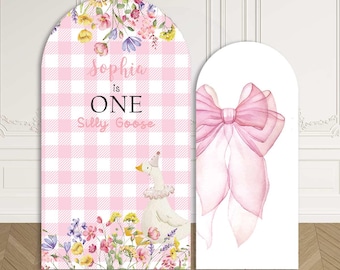 May include: Custom stretchy arch backdrop featuring a pink and white gingham pattern with floral accents. The backdrop includes the text "Sophia is ONE Silly Goose" and a watercolor illustration of a goose. A second backdrop shows a pink bow.