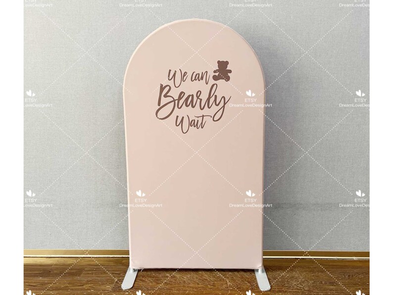 May include: A pink archway backdrop with the text "We can Bearly Wait" in brown script. A small brown teddy bear icon is above the text.