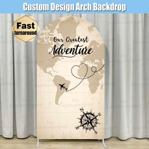 May include: A tan arch backdrop with a world map design and the text "Our Greatest Adventure". A compass with a black and white design is at the bottom of the backdrop.