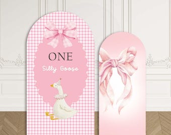 May include: Two arched fabric backdrops featuring a pink and white gingham pattern. The larger backdrop displays a pink scalloped frame, a large pink bow, the text ONE Silly Goose, and a white goose wearing a party hat. The smaller backdrop has a pink bow.