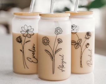 May include: Three frosted glass tumblers with bamboo lids and clear straws. Each tumbler has a black line drawing of a flower with a name at the bottom: Evelyn, Abigail, and Rachel.