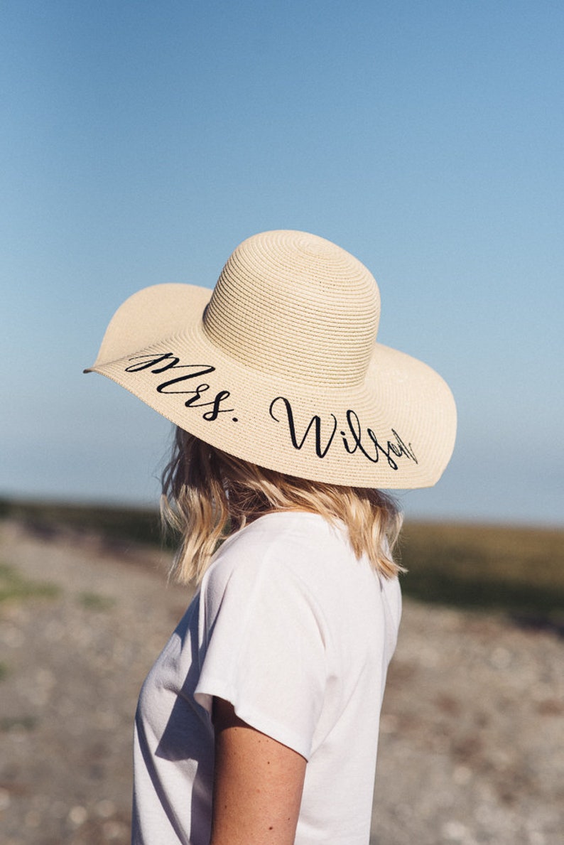 Puede incluir: Un sombrero de paja para el sol con un ala ancha y texto negro que dice "Mrs. Wilson".