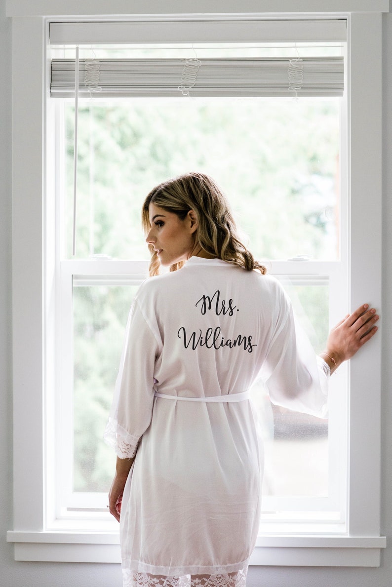 May include: A white satin robe with lace trim and the text "Mrs. Williams" printed on the back.