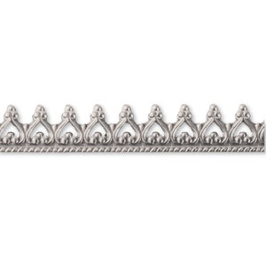 Könnte beinhalten: Silberne Verzierung mit einem sich wiederholenden Muster aus herzförmigen Ausschnitten und kleinen runden Akzenten.