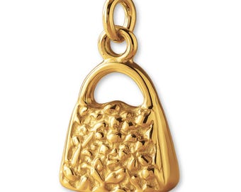 May include: A gold-toned metal charm shaped like a small handbag. The charm features a textured, bumpy surface on the front panel, a smooth arched handle, and a circular jump ring attached to the top for hanging on a chain or bracelet.